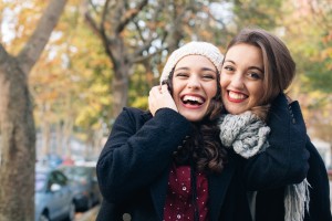 Laughing best friends hugging outdoors in autumn